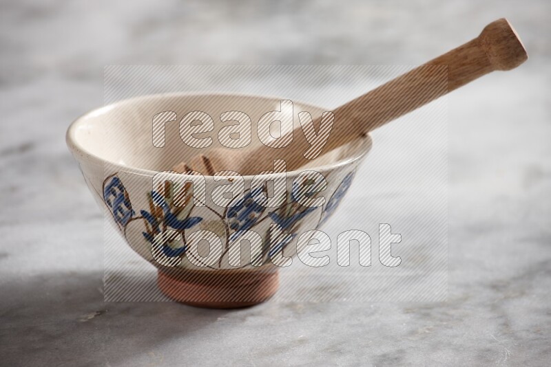 Decorative pottery bowl with wooden honey dipper in it on grey marble background