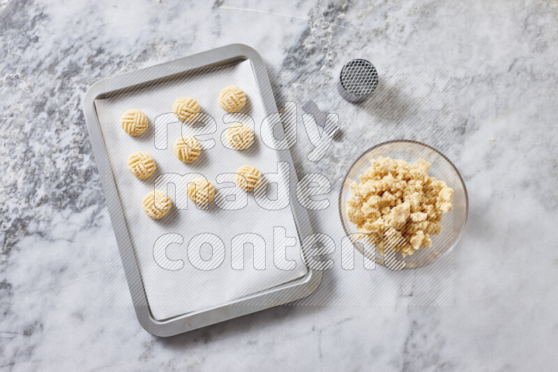 كحك خطوة بخطوة بمكوناته سمن، سكر، دقيق، سمسم، خميرة، ماء ونكهة الكحك على خلفية رخام رمادي