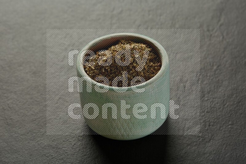 multi color round sauce bowl filled with herbs on grey textured countertop
