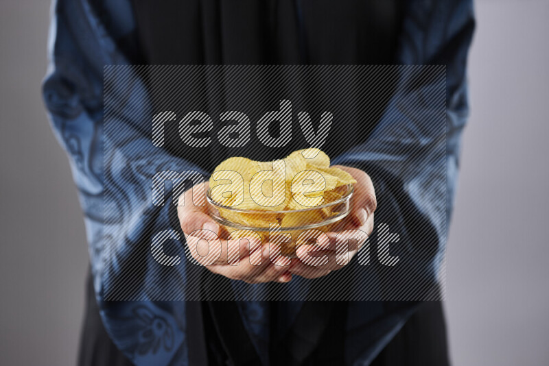 Woman in abaya holding different kinds of snacks in different positions