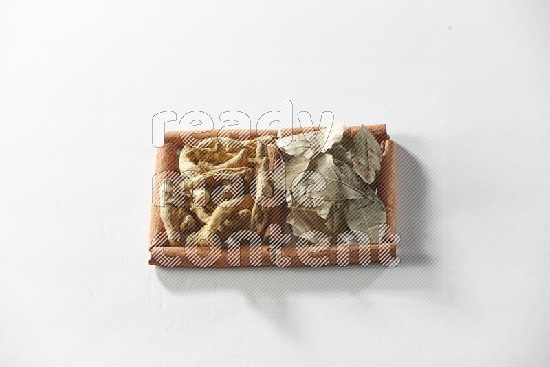 2 squares of cinnamon sticks full of turmeric fingers and bay laurel leaves on white flooring