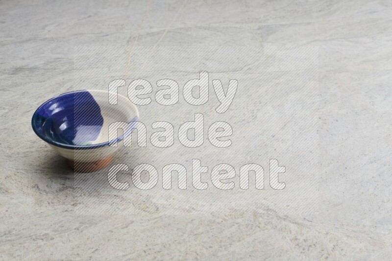 A multicolored pottery bowl on grey marble background