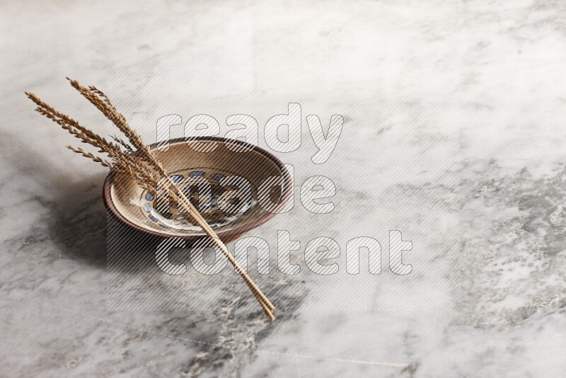 Wheat stalks on decorative pottery plate on grey marble background