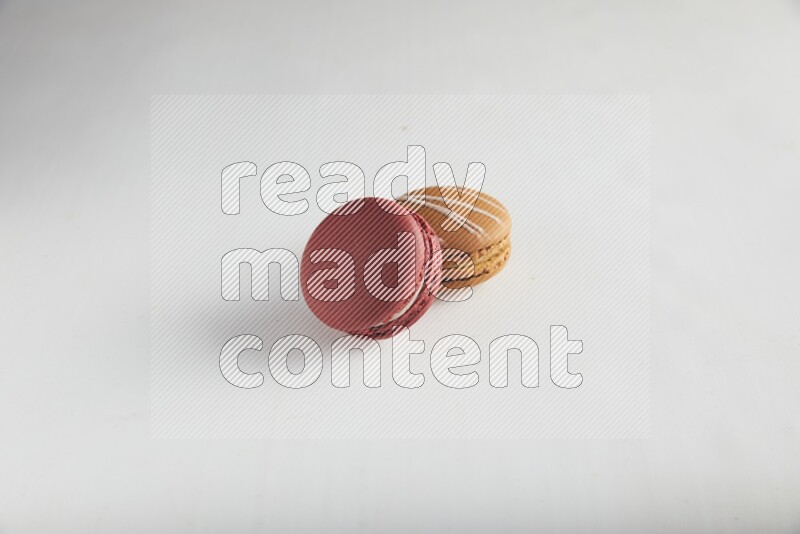 45º Shot of of two assorted Brown Irish Cream, and Red Velvet macarons on white background