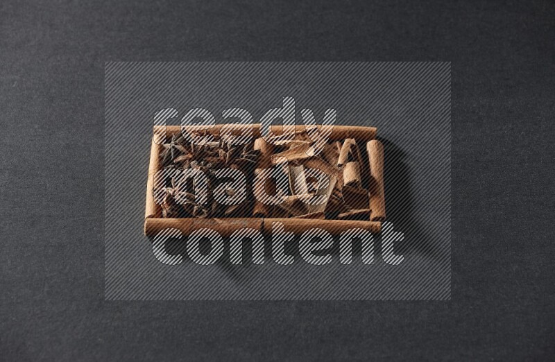 2 squares of cinnamon sticks full of star anise and cinnamon on black flooring