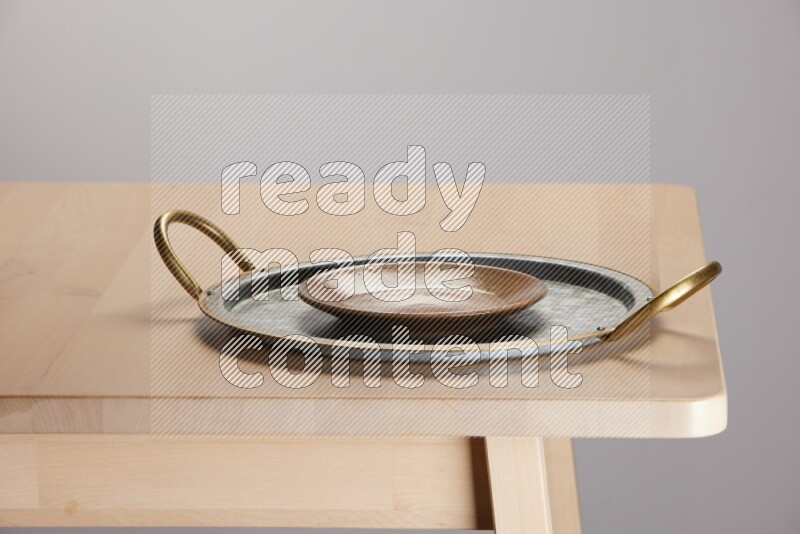 multicolored plate placed on a rounded stainless steel tray with golden handels on the edge of wooden table