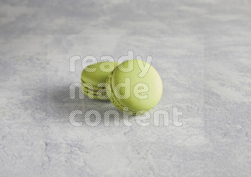 45º Shot of two Green Pistachio macarons  on white  marble background