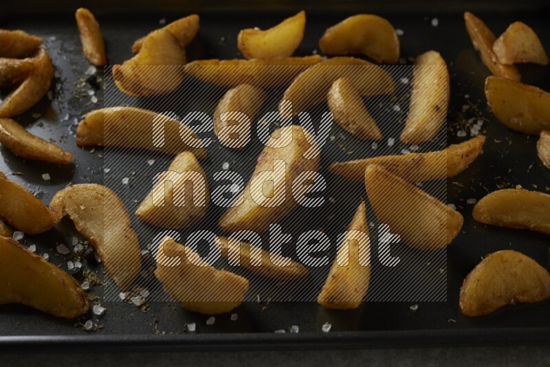 wedges potato in a black stainless steel rectangle tray on grey textured counter top