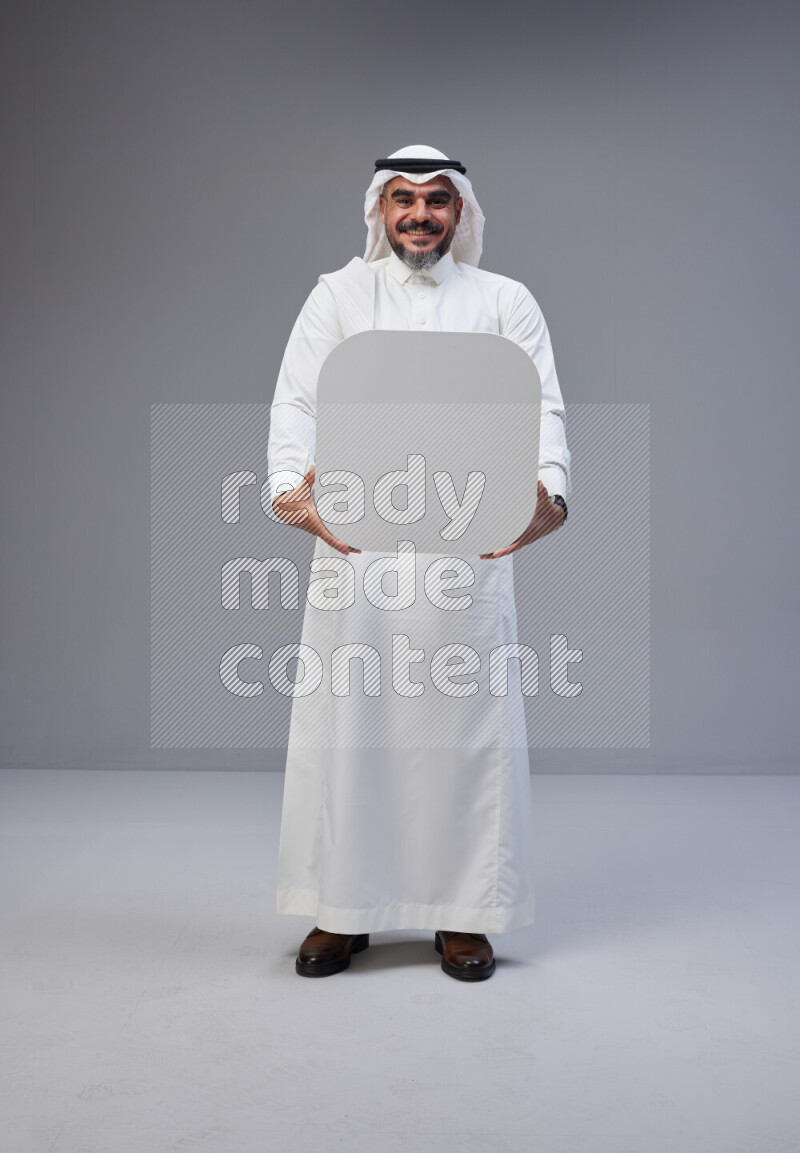 Saudi man Wearing Thob and white Shomag standing holding social media sign on Gray background
