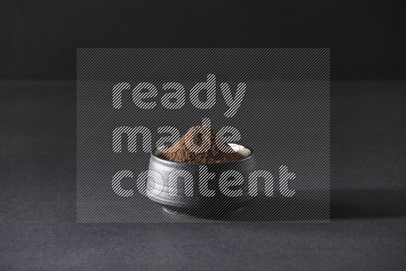 وعاء فخاري أسود ممتلئ ببودرة القرنفل علي خلفية سوداء