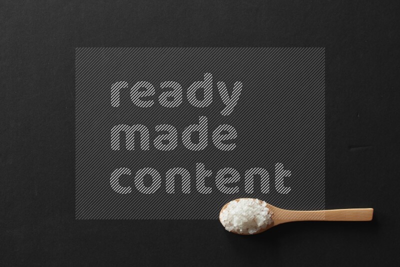 wooden spoons filled with white peppers, cloves, cardamom, salt, black peppers and basil on black flooring