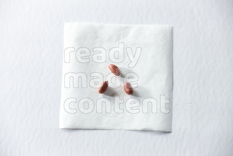 3 red skin peanuts on a piece of paper on a white background in different angles