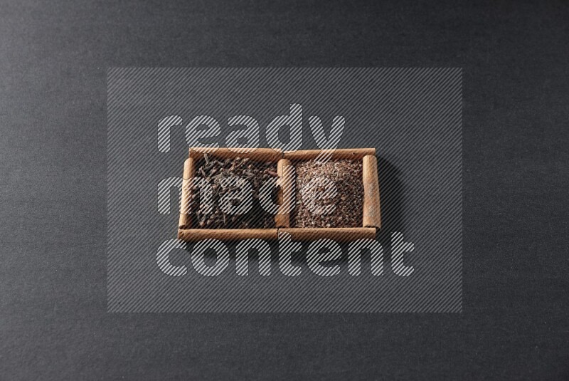 2 squares of cinnamon sticks full of flaxseeds and cloves on black flooring