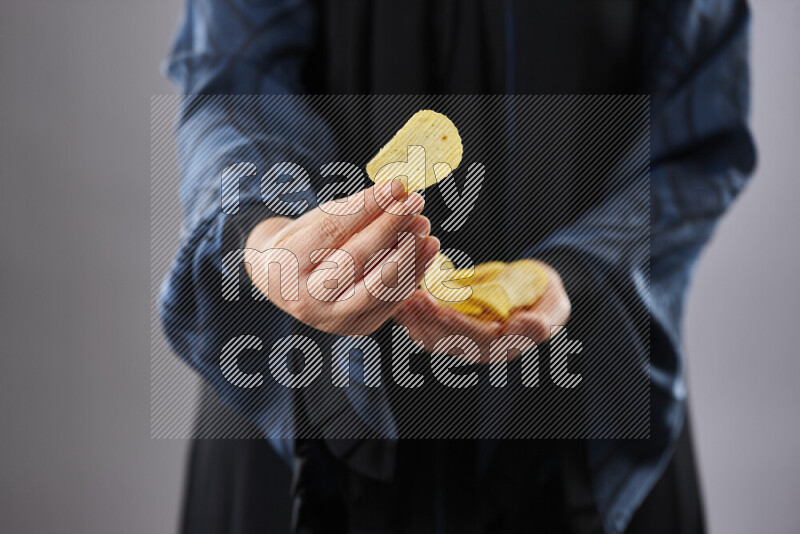 Woman in abaya holding different kinds of snacks in different positions