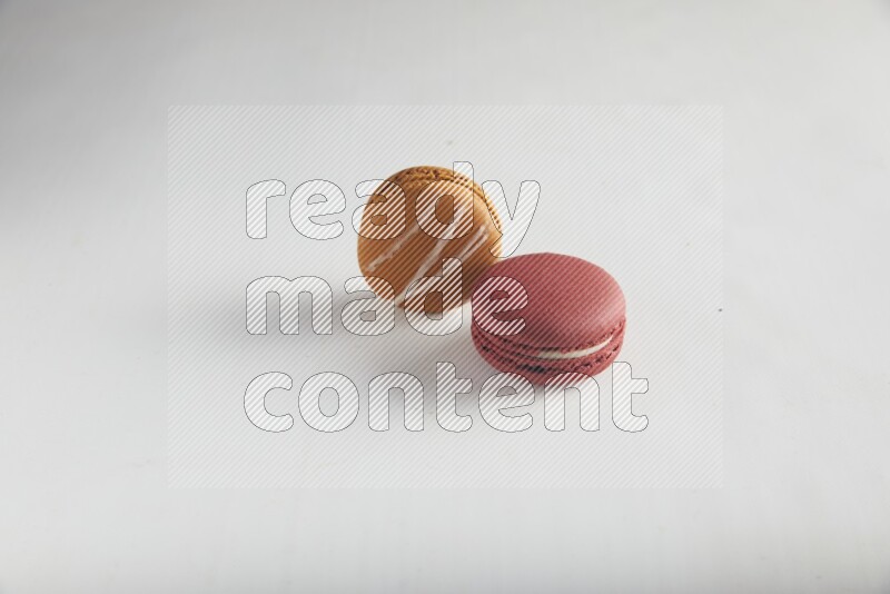 45º Shot of of two assorted Brown Irish Cream, and Red Velvet macarons on white background