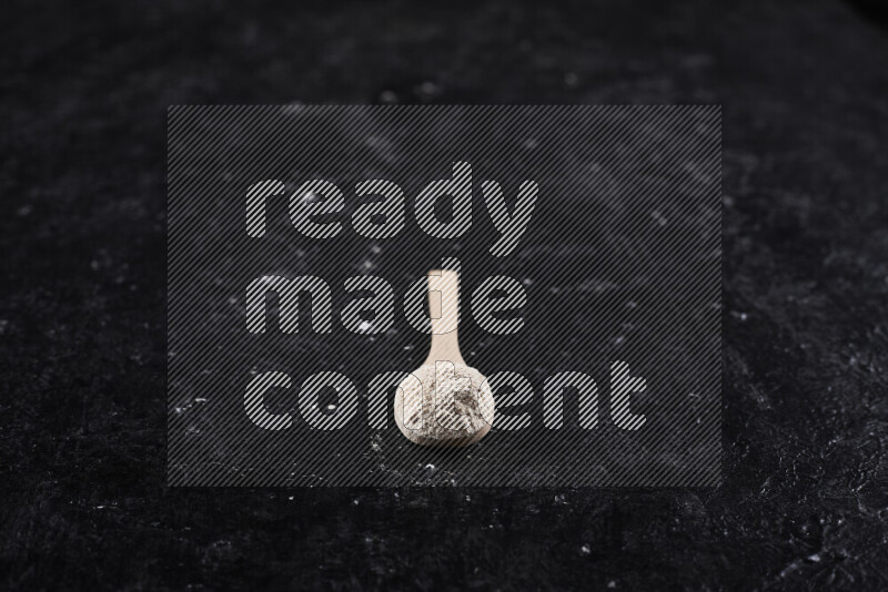 ملعقة خشبية ممتلئة ببودرة البصل علي خلفية سوداء