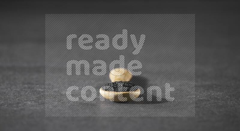 ملعقة خشبية ممتلئة بحبة البركة على أرضية سوداء