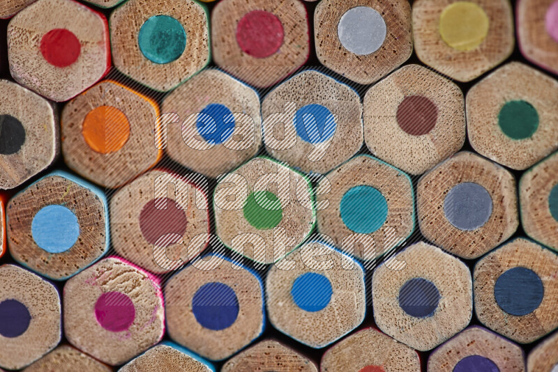 A close-up of the tips of colored pencils arranged in a bundle on white background