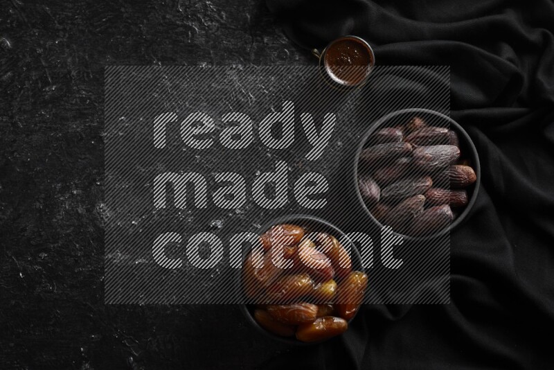 Dates in pottery bowls with coffee in a dark setup