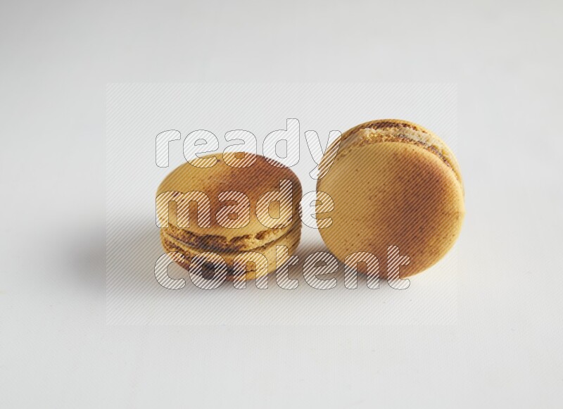 45º Shot of two Yellow Crème Brulée macarons on white background