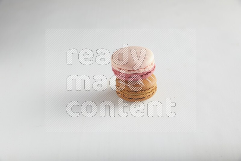 45º Shot of of two assorted Brown Irish Cream, and Pink Litchi Raspberry macarons on white background