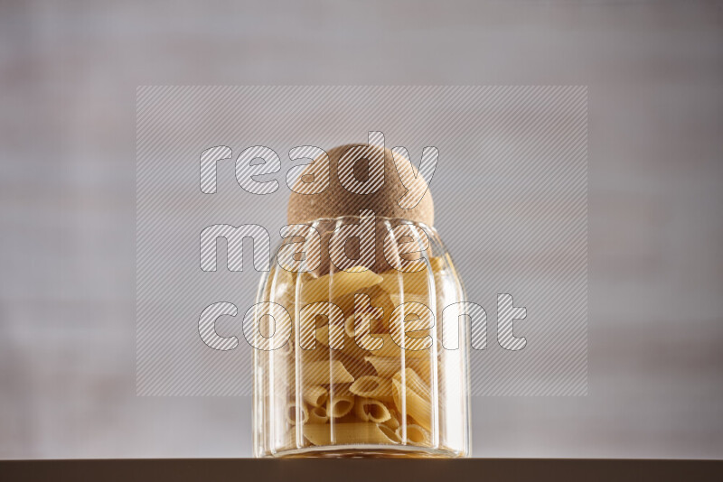 Raw pasta in glass jars on beige background