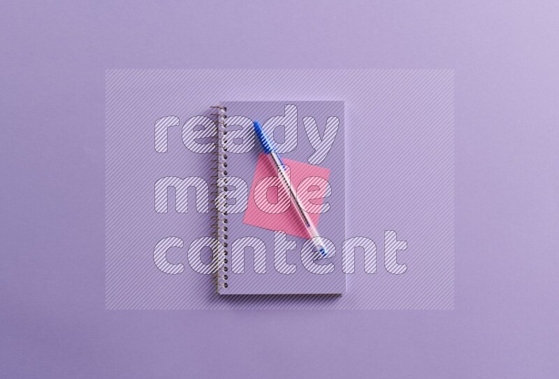 A purple notebook with different school supplies on purple background