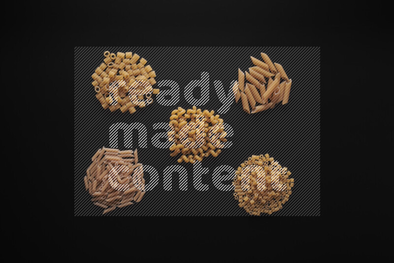 Different pasta types in bunches on black background