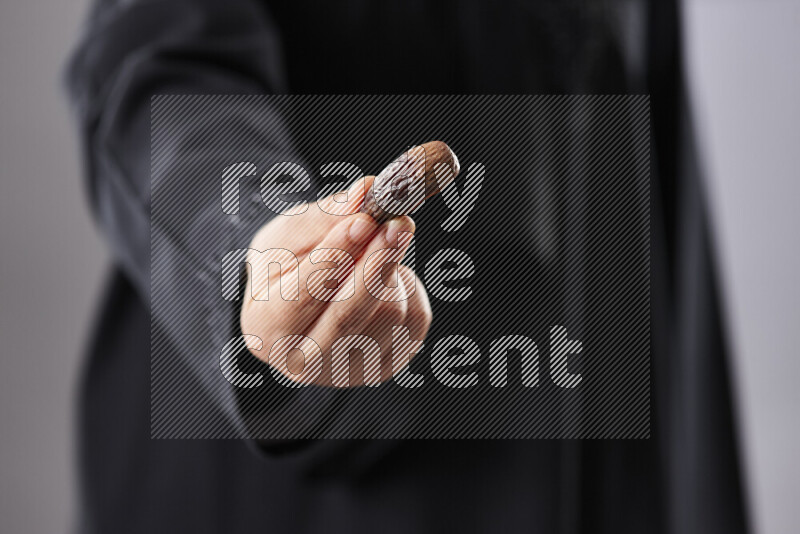 Woman in abaya holding dates in different positions