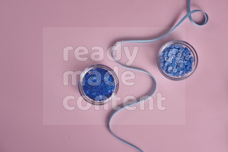 A blue collection of sewing and tailoring tools arranged on a pink background