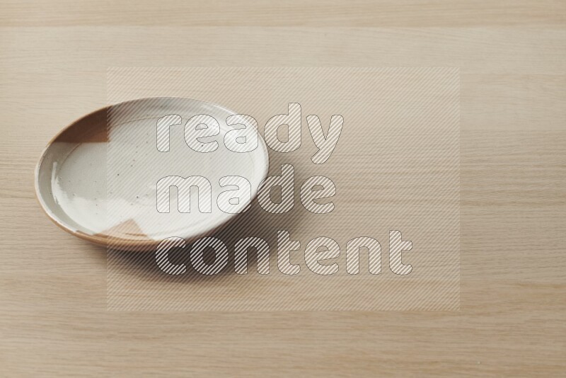 A multicolored pottery plate on light wooden background
