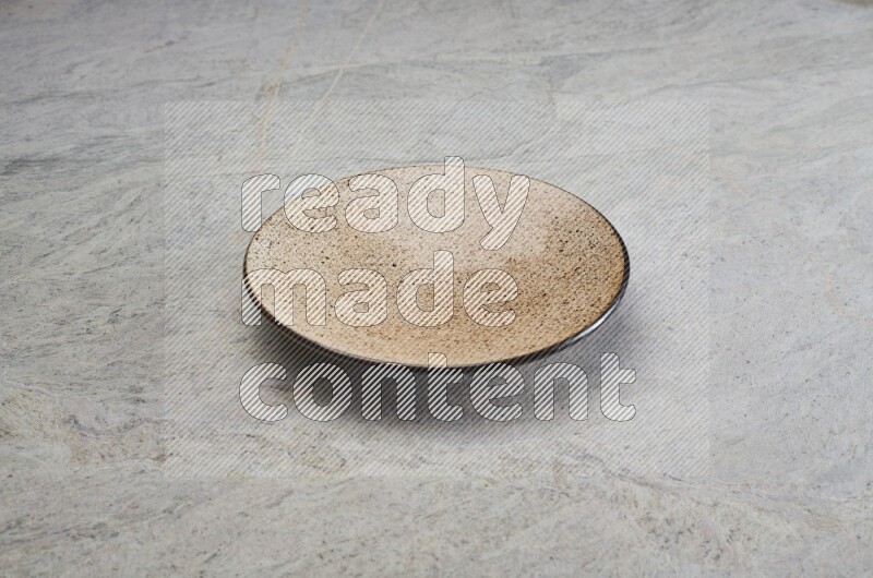 A beige pottery plate on grey marble background