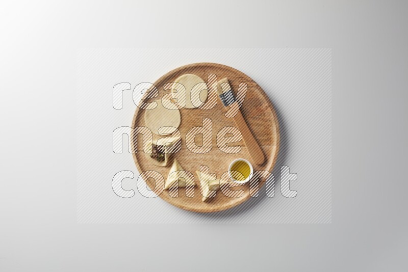 two closed sambosas and one open sambosa filled with meat while oil with oil brush aside in a wooden dish on a white background