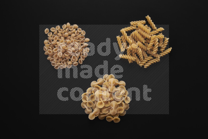 Different pasta types in bunches on black background