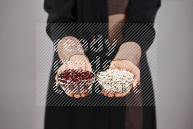 Woman in abaya holding different kinds of legumes in different positions