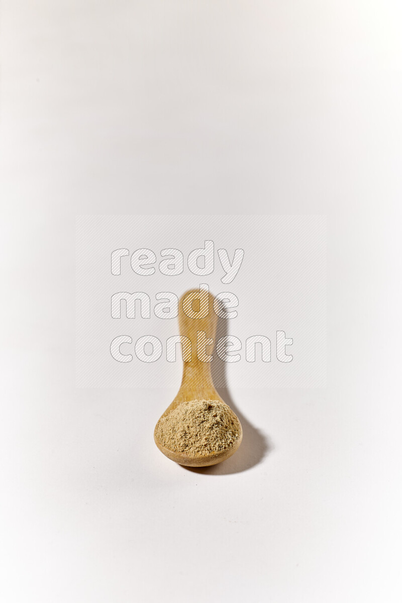 A wooden spoon full of ground ginger powder on white background