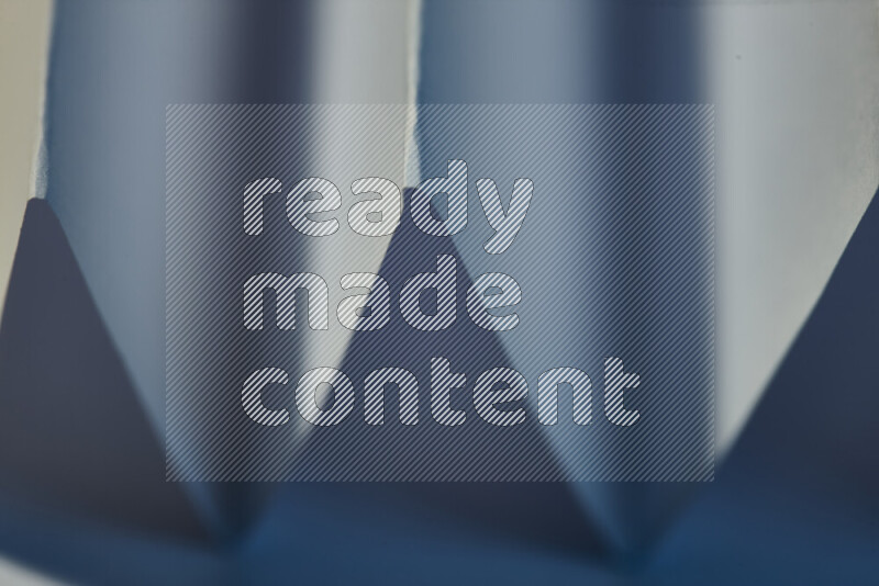 صورة مجردة مقربة تظهر طيات ورقية هندسية حادة بتدرجات اللون الأزرق