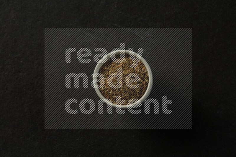 white ceramic round sauce bowl filled with herbs on grey textured countertop