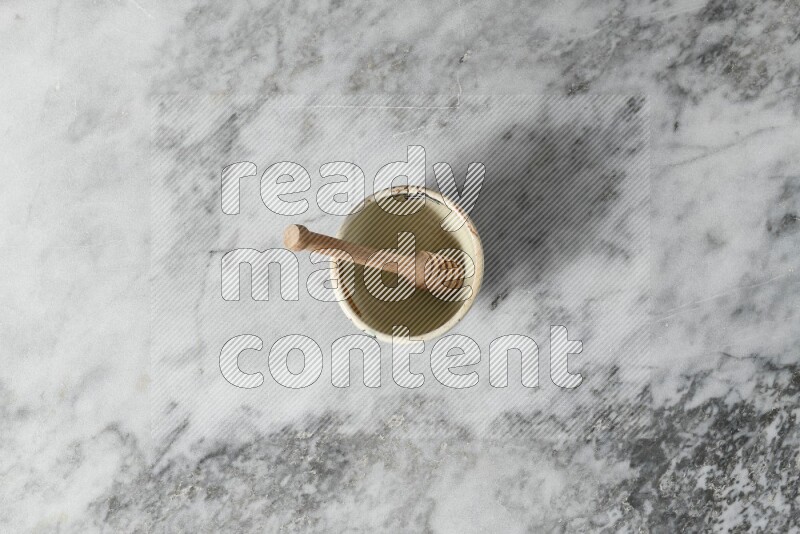 Decorative pottery bowl with wooden honey dipper in it on grey marble background