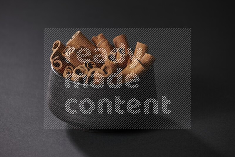 Cinnamon sticks in a black bowl on a black background in different angles