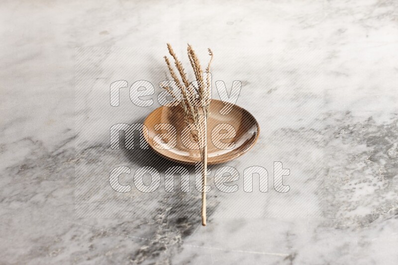 Wheat stalks on multicolored pottery plate on grey marble background