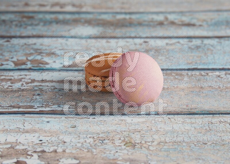 45º Shot of of two assorted Brown Irish Cream, and Purple Strawberry macarons  on light blue background