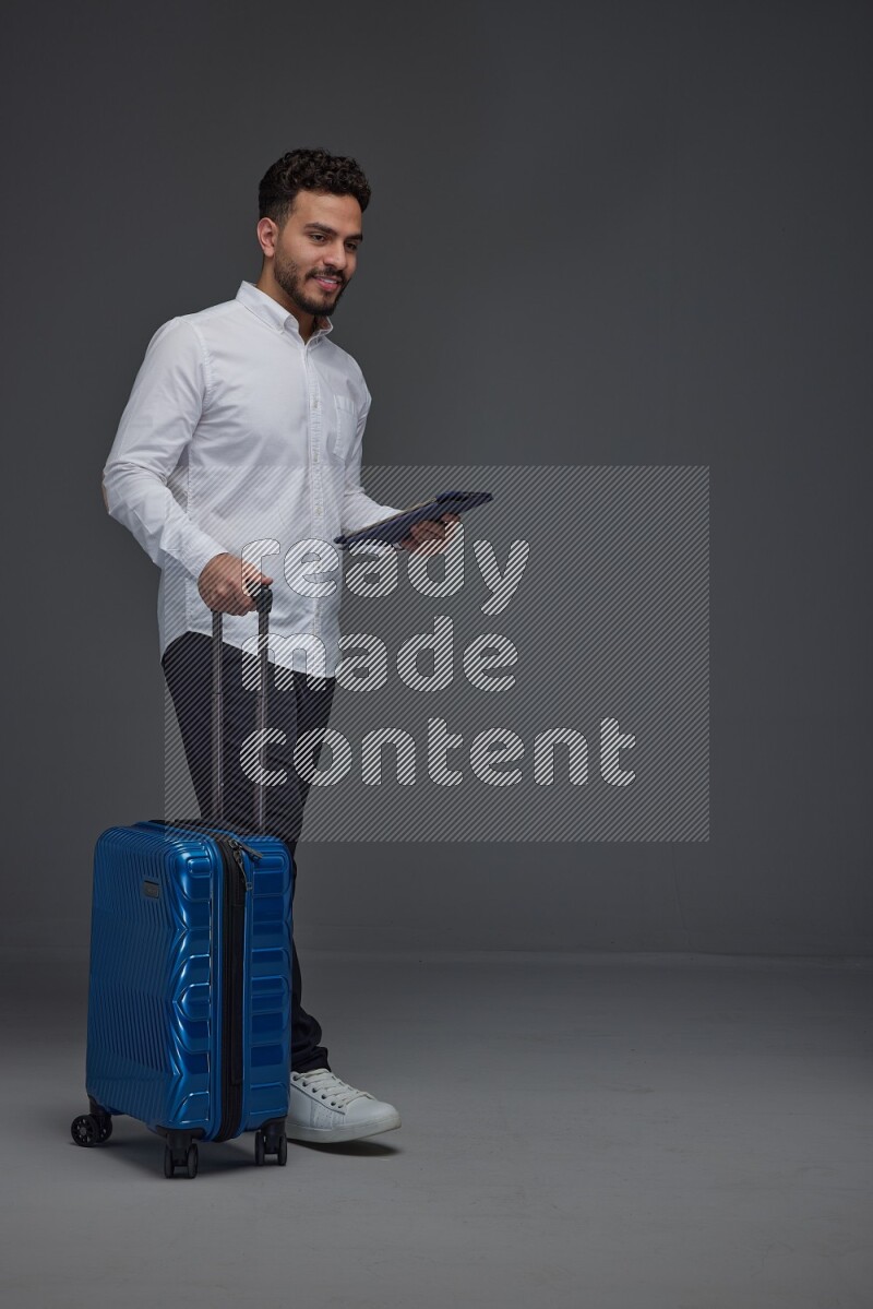 A man wearing smart casual with and pulling a carry-on luggage eye level on a gray background
