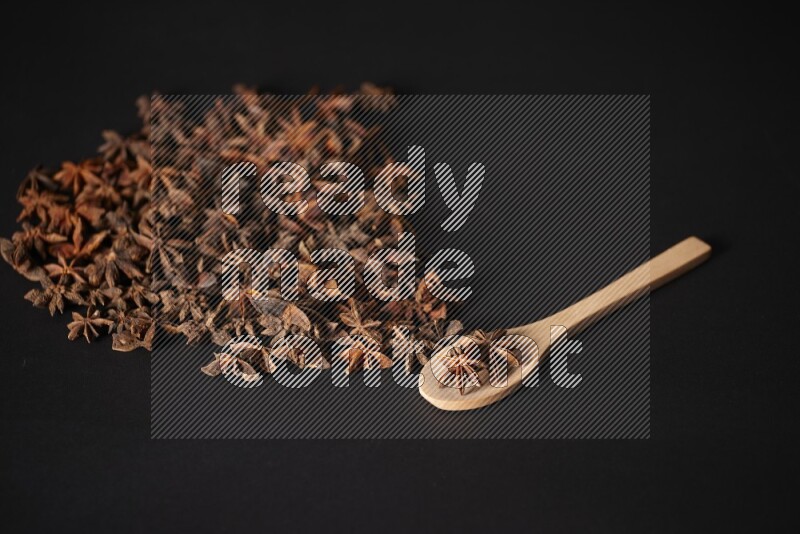 Star Anise in a wooden spoon and spreading on a black flooring