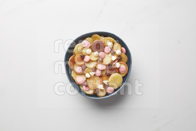 Top-view shot of mixed chocolate chips cereal pancakes in a round bowl on white background