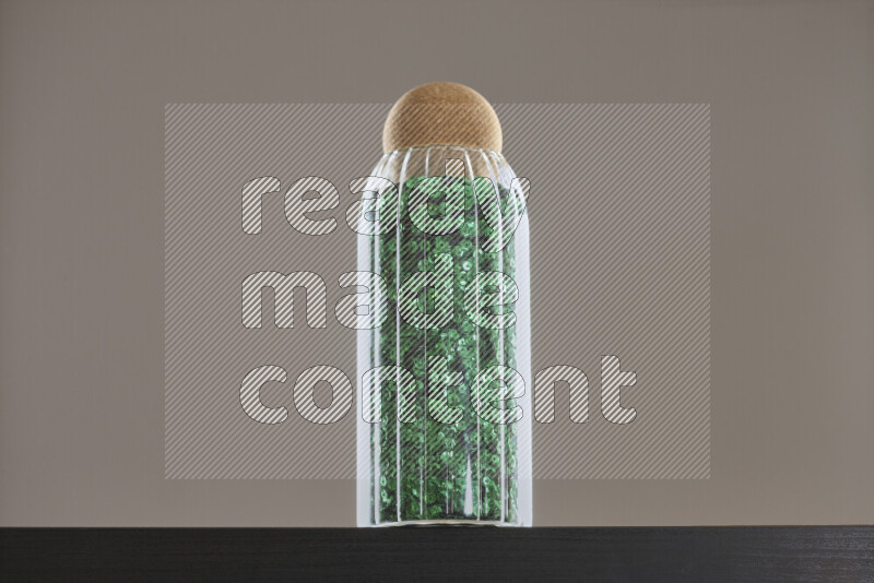 Sequins in a glass jar on black background