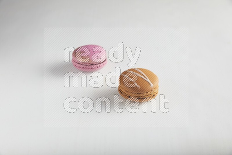 45º Shot of of two assorted Brown Irish Cream, and Purple Strawberry macarons on white background