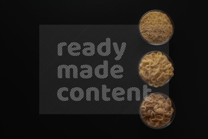 Different pasta types in 3 glass bowls on black background