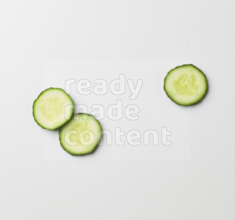 three cucumber slices on white background