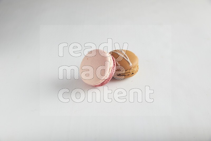 45º Shot of of two assorted Brown Irish Cream, and Pink Litchi Raspberry macarons on white background